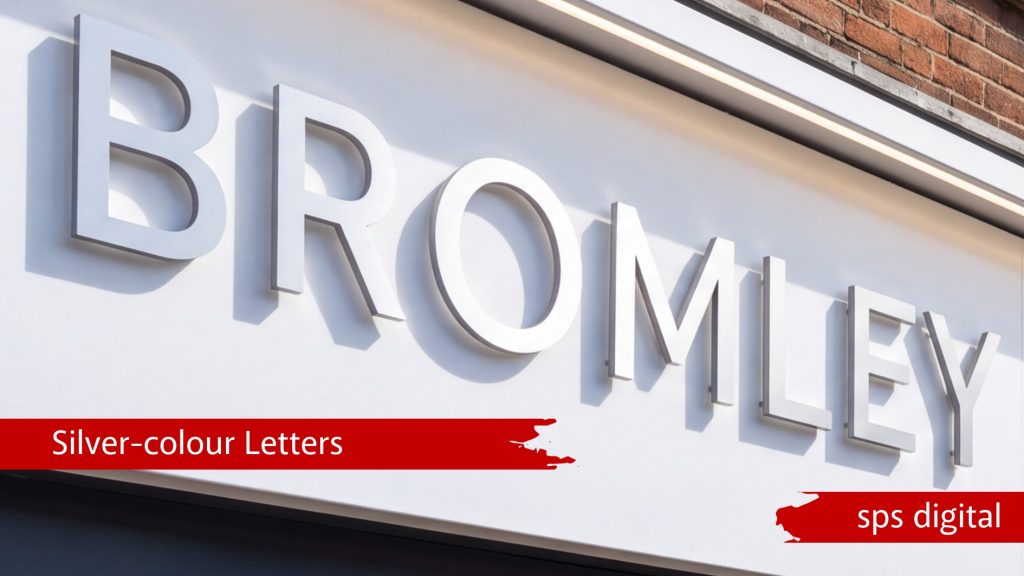 Silver‑colour 3D “BROMLEY” letters mounted on a smooth white fascia with crisp reflective metal finish, shown with brick detailing above and clean modern shopfront styling, capturing premium craftsmanship and a high‑quality SPS Digital commercial signage presentation.